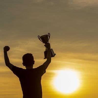 A person holding up a trophy in a celebratory pose